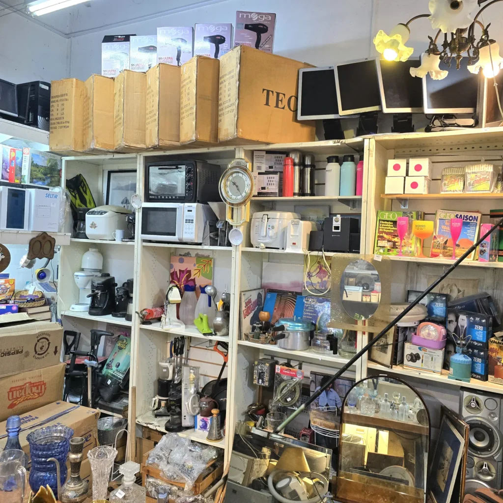 Tienda de segunda mano con estantes llenos de electrodomésticos, electrónica y artículos para el hogar. by Remates Narvaja