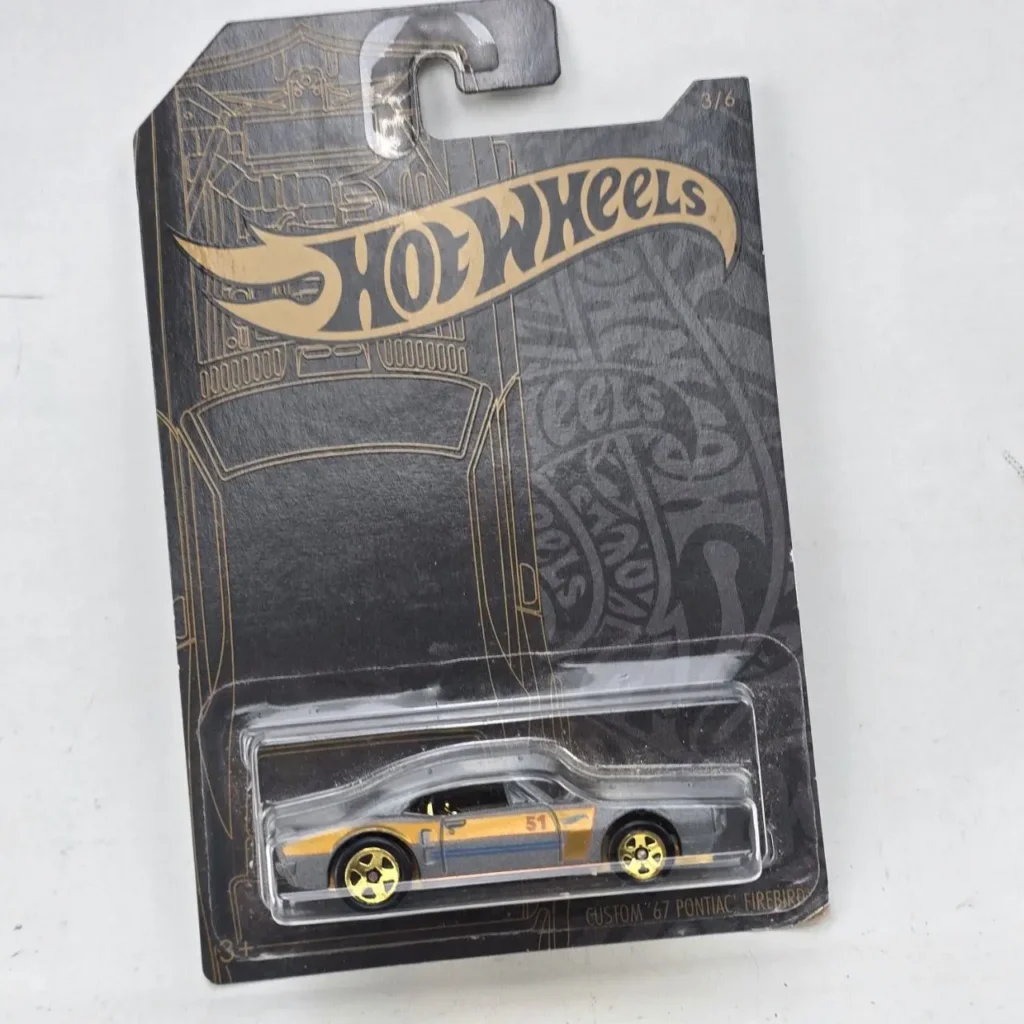 Hot Wheels Custom '67 Pontiac Firebird gris con franja dorada, en empaque negro y dorado original." by Remates Narvaja