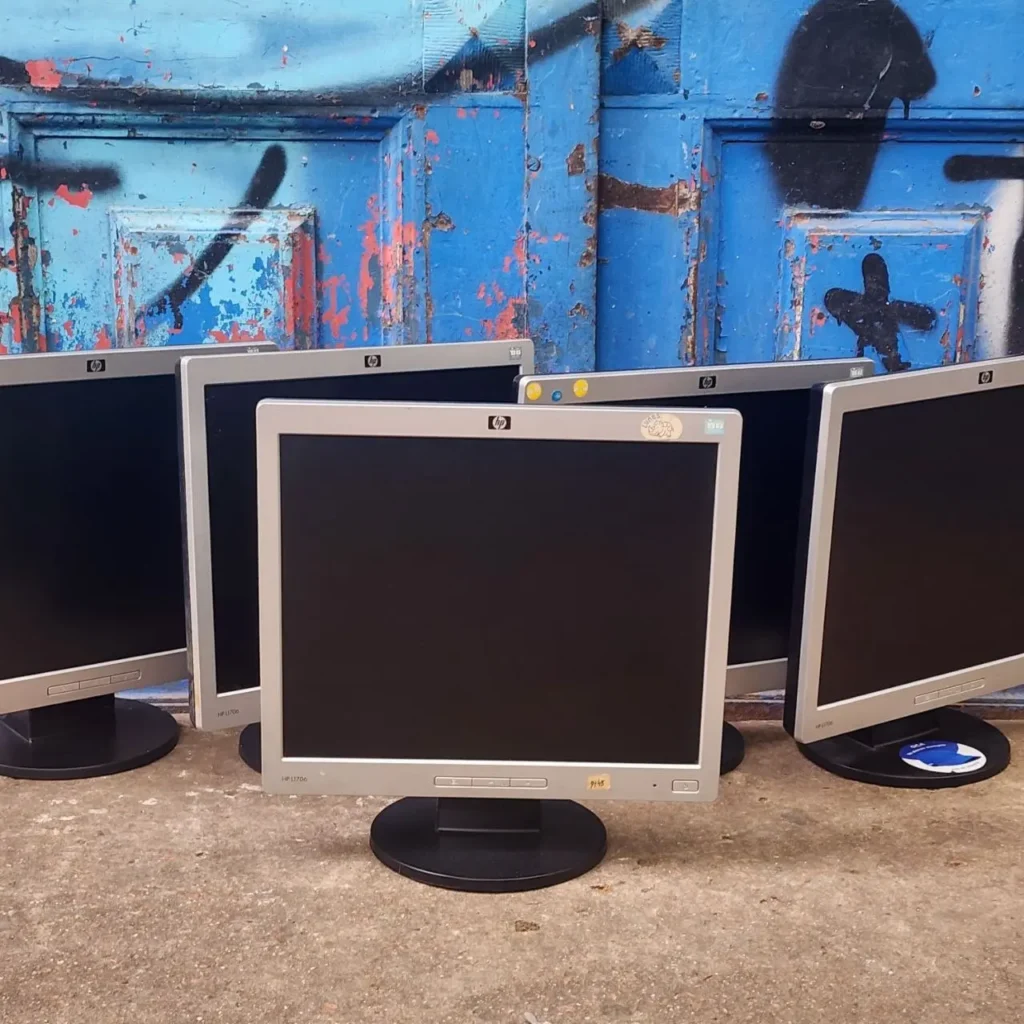 Monitores HP L1706 usados sobre suelo de hormigón con pared azul grafitada. by Remates Narvaja