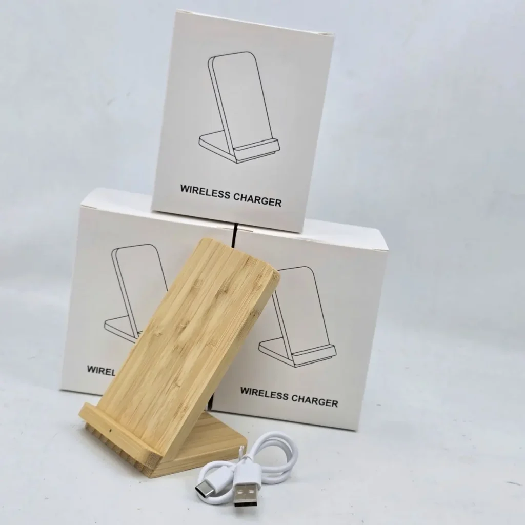 Base de carga inalámbrica de bambú junto a tres cajas blancas de cargadores inalámbricos y un cable USB blanco. by Remates Narvaja