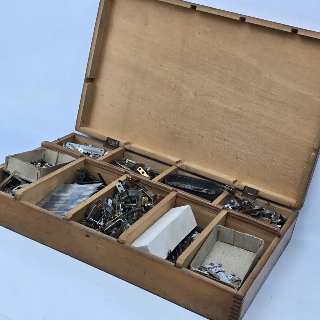 Caja de madera vintage abierta con compartimentos llenos de piezas metálicas y herrajes. by Remates Narvaja